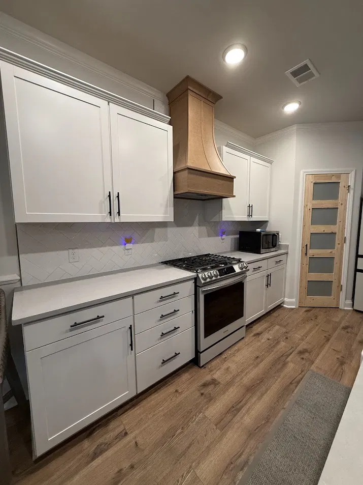 Kitchen remodel with white shaker cabinets, herringbone backsplash, and custom wood range hood by CNB Renovations